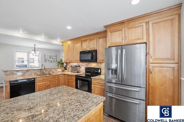 kitchen with decorative backsplash, a sink, light stone counters, and black appliances