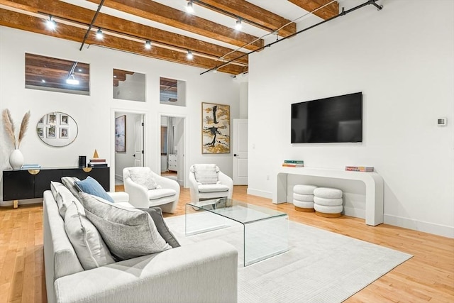 33 Sleeper St Unit 106, Boston, MA 02210 - living room featuring rail lighting, beam ceiling, wood finished floors, and a towering ceiling