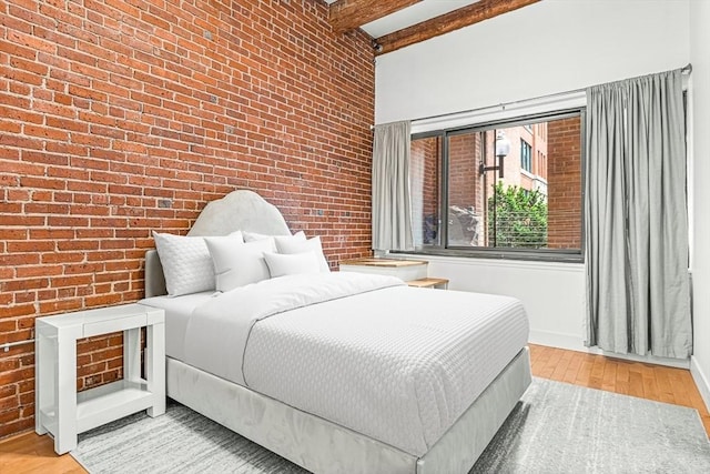 33 Sleeper St Unit 106, Boston, MA 02210 - bedroom with brick wall, light wood-type flooring, and beam ceiling