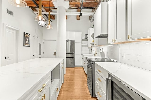 33 Sleeper St Unit 106, Boston, MA 02210 - kitchen with stainless steel appliances, beverage cooler, light wood-style flooring, backsplash, and a high ceiling