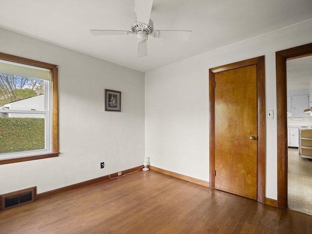 empty room featuring wood finished floors, a ceiling fan, and baseboards