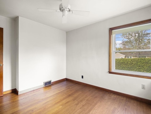 empty room with wood finished floors, baseboards, and a ceiling fan