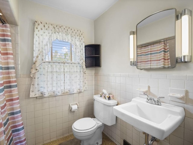 full bath with a sink, toilet, tile walls, a wainscoted wall, and curtained shower
