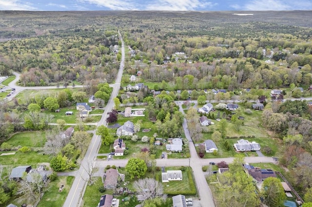 aerial view of property and surrounding area with a heavily wooded area and nearby suburban area