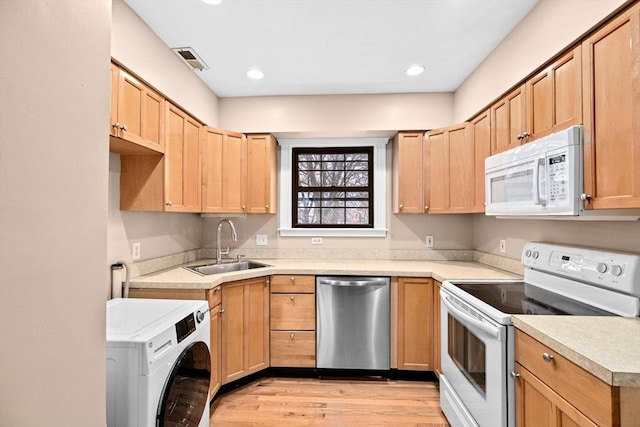 kitchen featuring light hardwood / wood-style floors, white appliances, washer / dryer, and sink