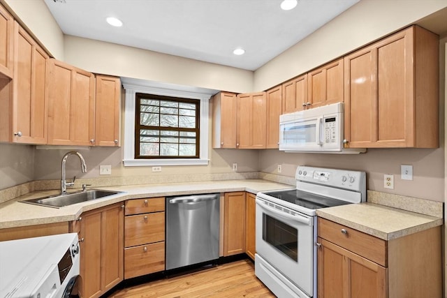 kitchen featuring sink, white appliances, light hardwood / wood-style flooring, and light brown cabinets