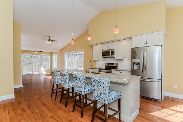 kitchen with light wood-style flooring, appliances with stainless steel finishes, a kitchen breakfast bar, and a sink