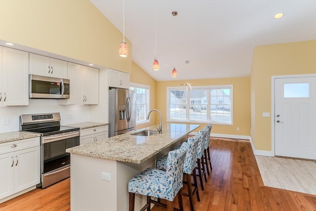 kitchen with a sink, light wood-style floors, appliances with stainless steel finishes, and white cabinetry