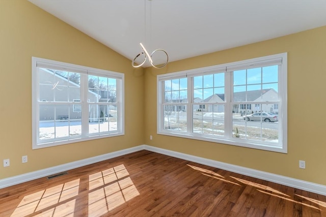 unfurnished dining area featuring visible vents, baseboards, lofted ceiling, and wood finished floors