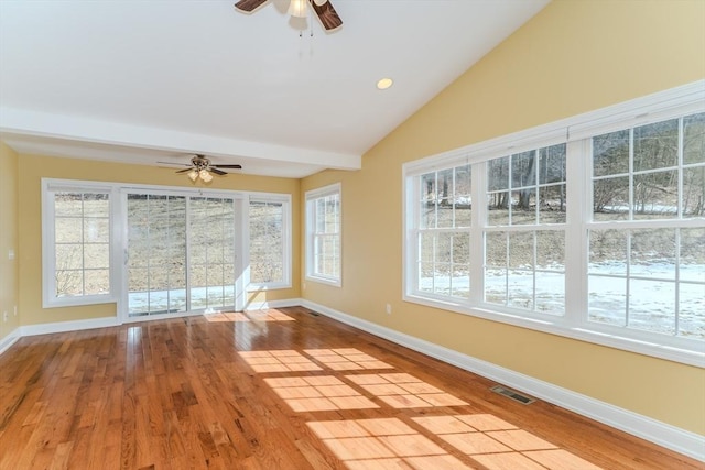 unfurnished room with vaulted ceiling, visible vents, baseboards, and wood finished floors