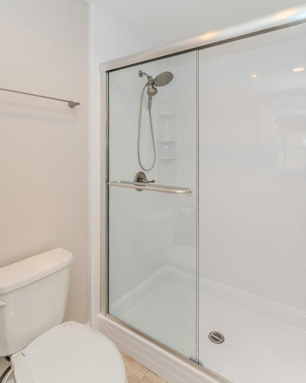 full bath with tile patterned flooring, a stall shower, and toilet