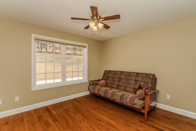 living area with ceiling fan, visible vents, baseboards, and wood finished floors