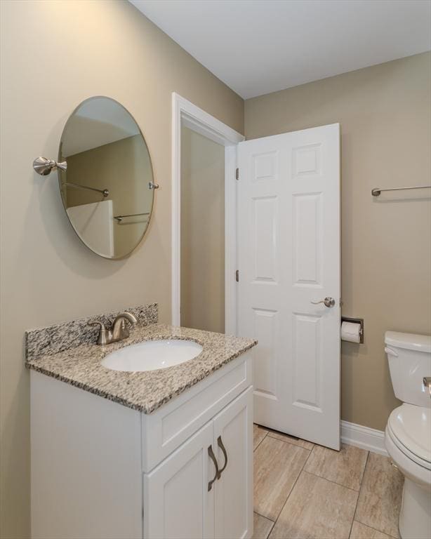 bathroom featuring toilet, vanity, and baseboards