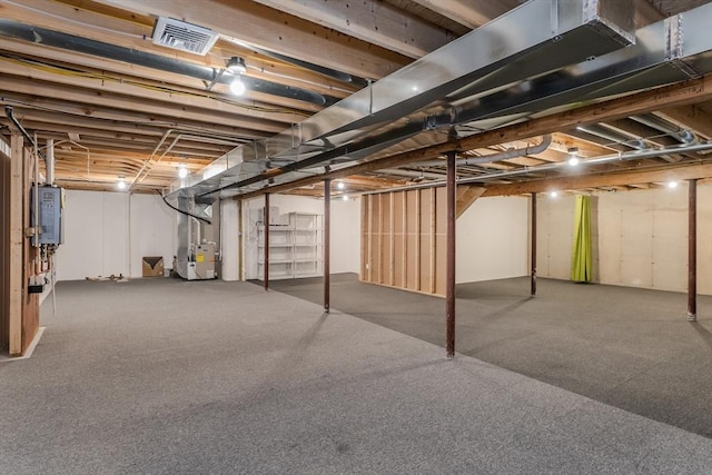 unfinished basement featuring visible vents, heating unit, and water heater