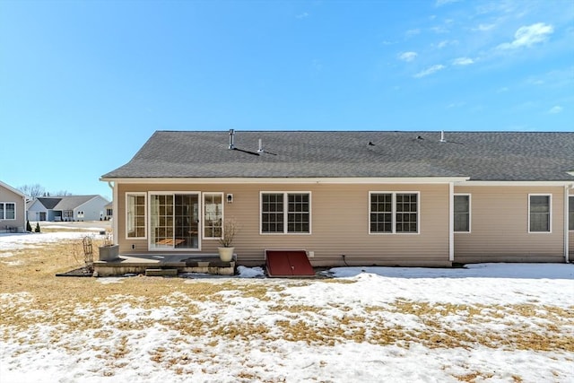 snow covered property featuring a shingled roof