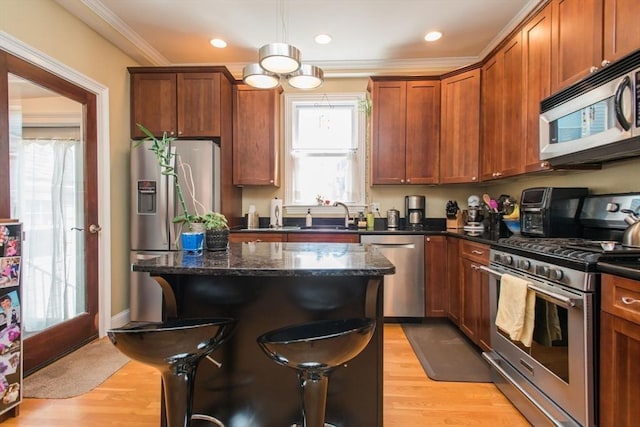 kitchen featuring a healthy amount of sunlight, appliances with stainless steel finishes, ornamental molding, and a kitchen island