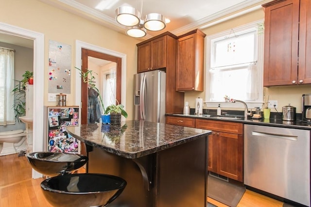 kitchen with appliances with stainless steel finishes, brown cabinetry, a wealth of natural light, and light wood-style flooring