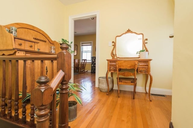 hall with baseboards, visible vents, and wood finished floors