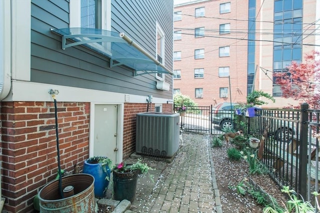 view of side of home with brick siding, fence, and cooling unit
