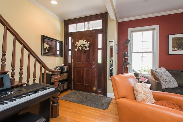 foyer with crown molding, wood finished floors, and stairway