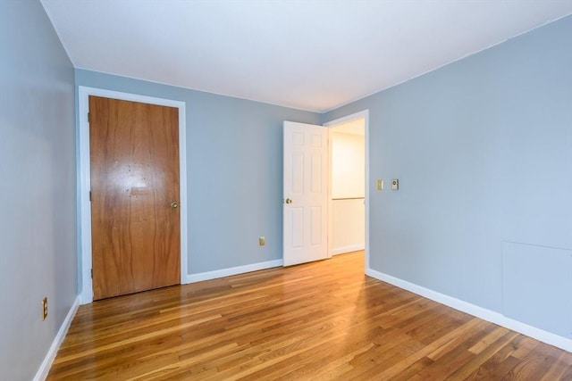 unfurnished bedroom featuring a closet, baseboards, and wood finished floors