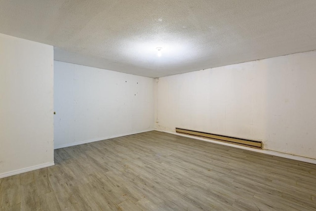 empty room with a baseboard radiator, baseboards, light wood-style flooring, and a textured ceiling