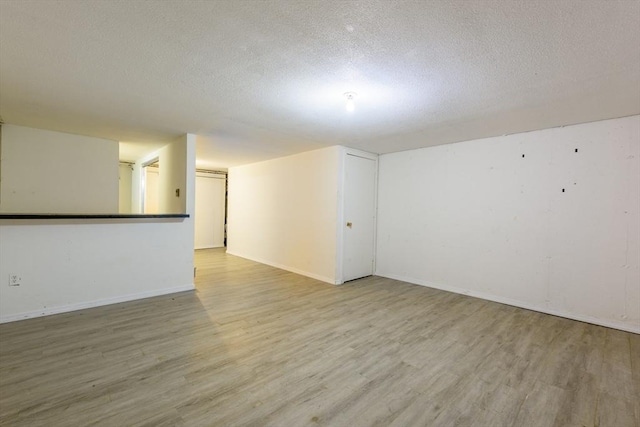 unfurnished room featuring light wood-style floors, a textured ceiling, and baseboards