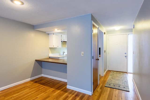 hall with light wood-type flooring and baseboards