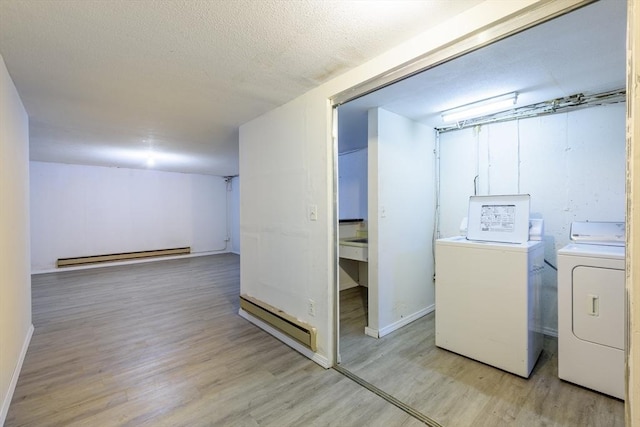 washroom featuring light wood-style floors, a baseboard radiator, laundry area, and washer and clothes dryer