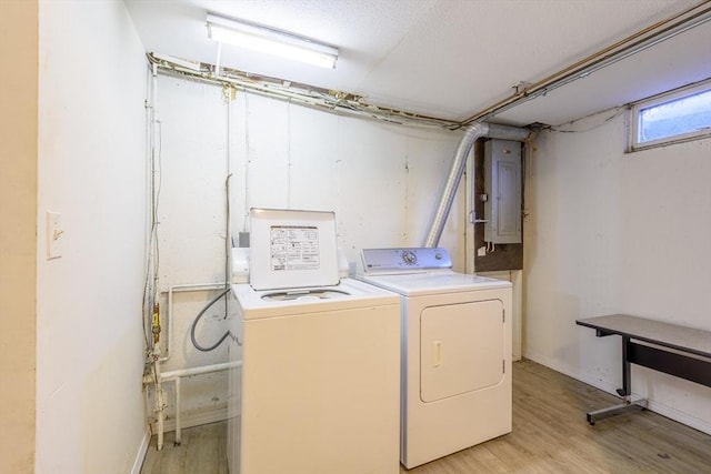 clothes washing area featuring washer and dryer, laundry area, electric panel, and light wood finished floors