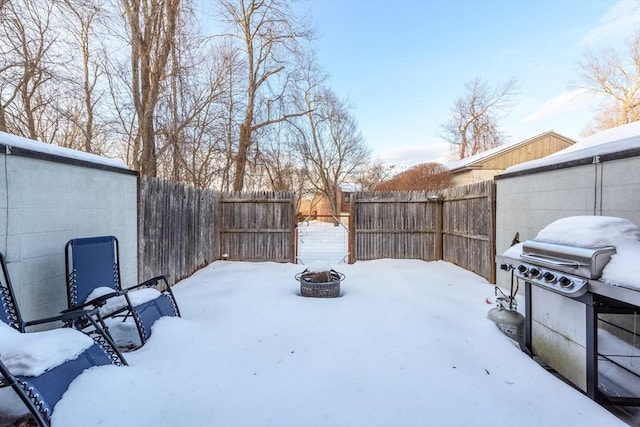 snowy yard featuring an outdoor fire pit and a fenced backyard