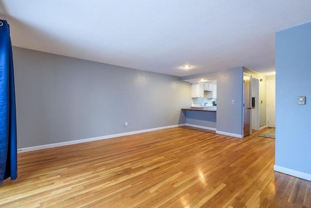 unfurnished living room featuring baseboards and light wood finished floors