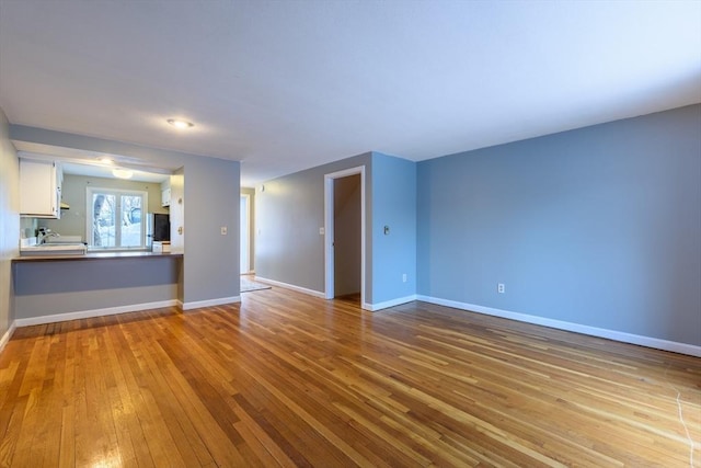 unfurnished living room featuring light wood-type flooring and baseboards