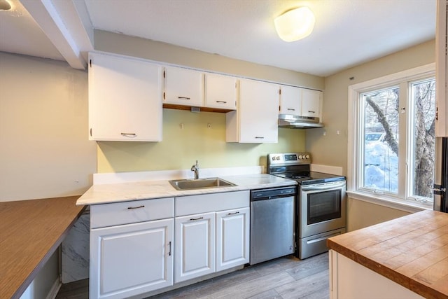 kitchen featuring appliances with stainless steel finishes, white cabinets, a sink, and under cabinet range hood