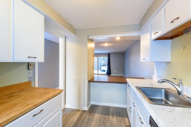 kitchen featuring white cabinetry, light countertops, a sink, and wood finished floors