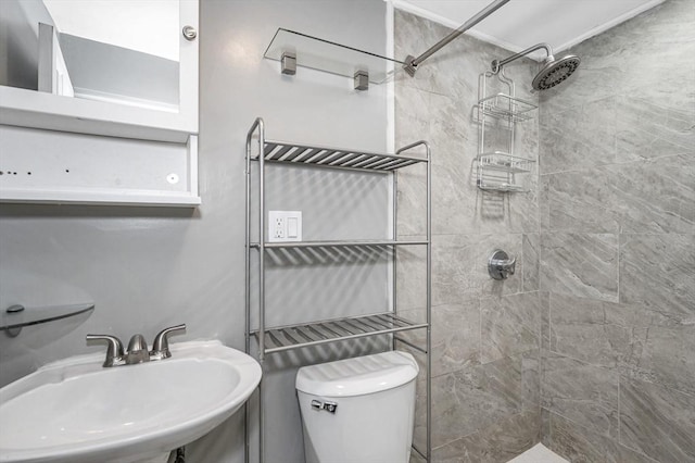 full bath featuring a tile shower, toilet, and a sink