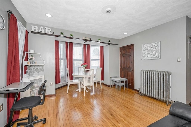 dining space with radiator, light wood-style flooring, baseboards, and recessed lighting