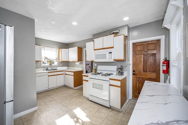kitchen with recessed lighting, white cabinetry, a sink, and white appliances