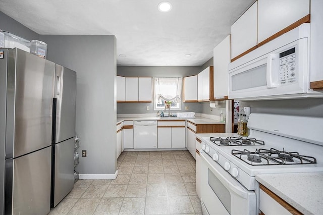kitchen with white cabinetry, baseboards, a sink, and white appliances
