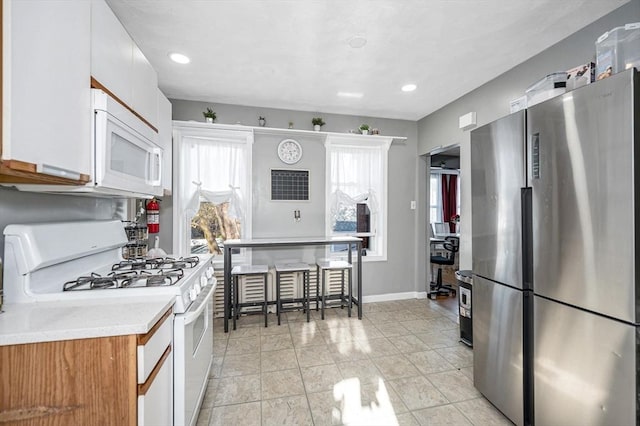 kitchen with white appliances, light countertops, a healthy amount of sunlight, and recessed lighting
