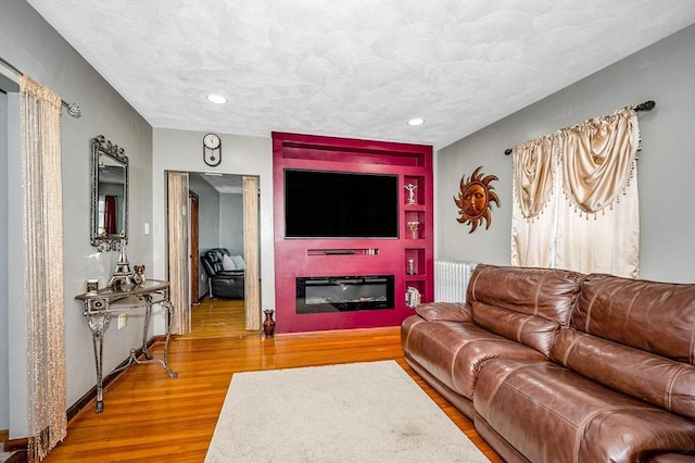 living room featuring recessed lighting, wood finished floors, and a glass covered fireplace