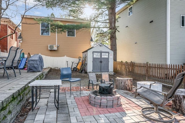 view of patio / terrace with an outdoor structure, area for grilling, a shed, a fenced backyard, and an outdoor fire pit