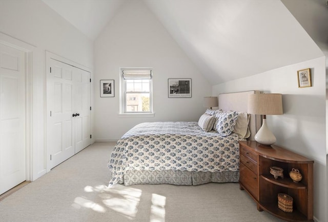 bedroom with lofted ceiling, light colored carpet, and a closet