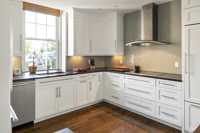 kitchen with wall chimney range hood, white cabinetry, black electric stovetop, decorative backsplash, and stainless steel dishwasher