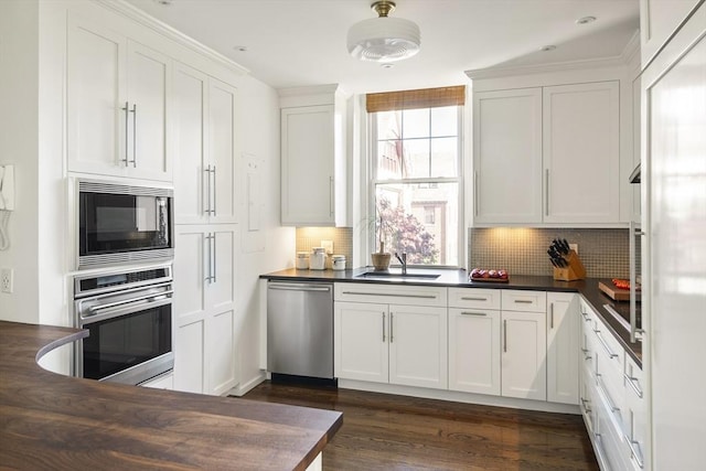 kitchen featuring appliances with stainless steel finishes, sink, white cabinets, and decorative backsplash