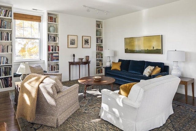 living room with rail lighting, dark hardwood / wood-style floors, and built in shelves