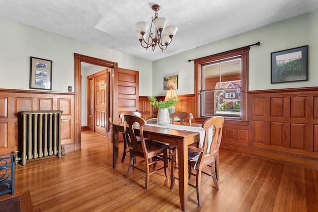 dining space with radiator, light hardwood / wood-style flooring, and a chandelier