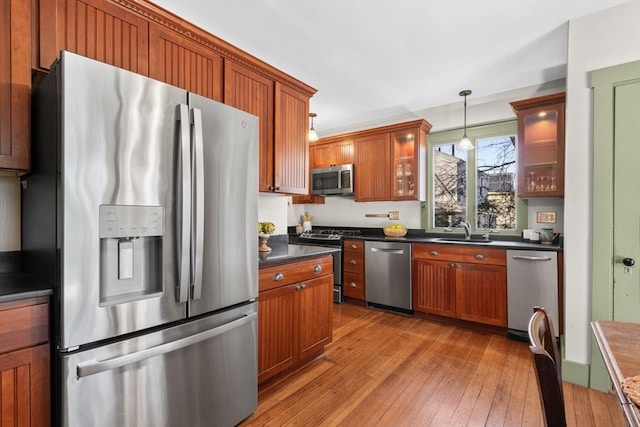 kitchen featuring appliances with stainless steel finishes, decorative light fixtures, light hardwood / wood-style floors, and sink