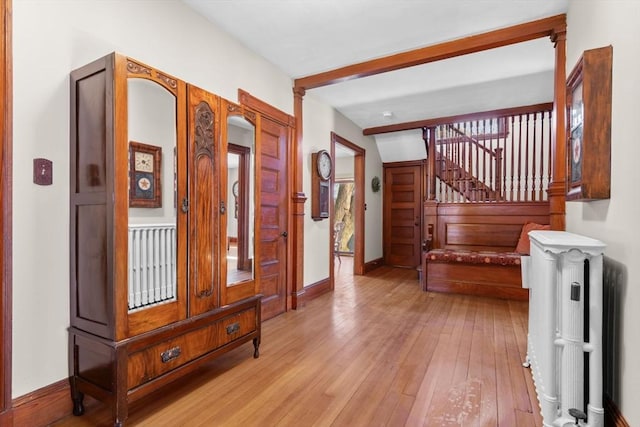 hall featuring radiator heating unit, beam ceiling, and light hardwood / wood-style flooring