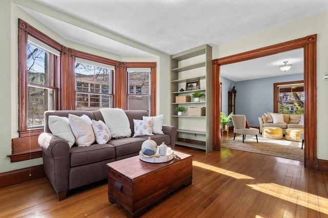 living room featuring hardwood / wood-style flooring, built in features, and a healthy amount of sunlight